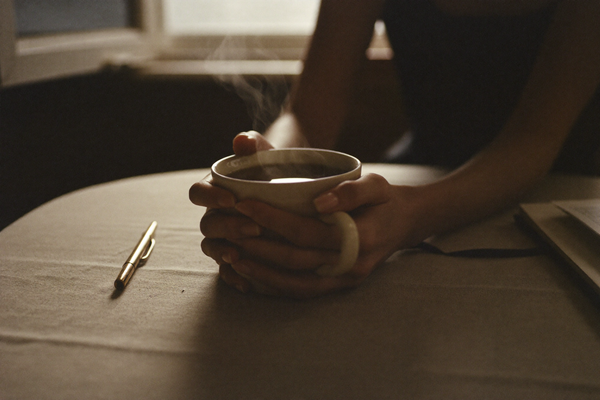 Close-up of a woman's hands holding a warm ceramic mug in morning light